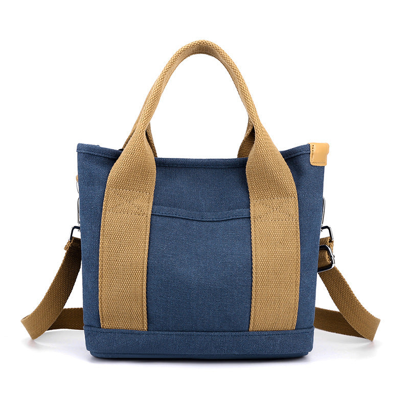 Blue tote bag with brown handles and strap on a white background