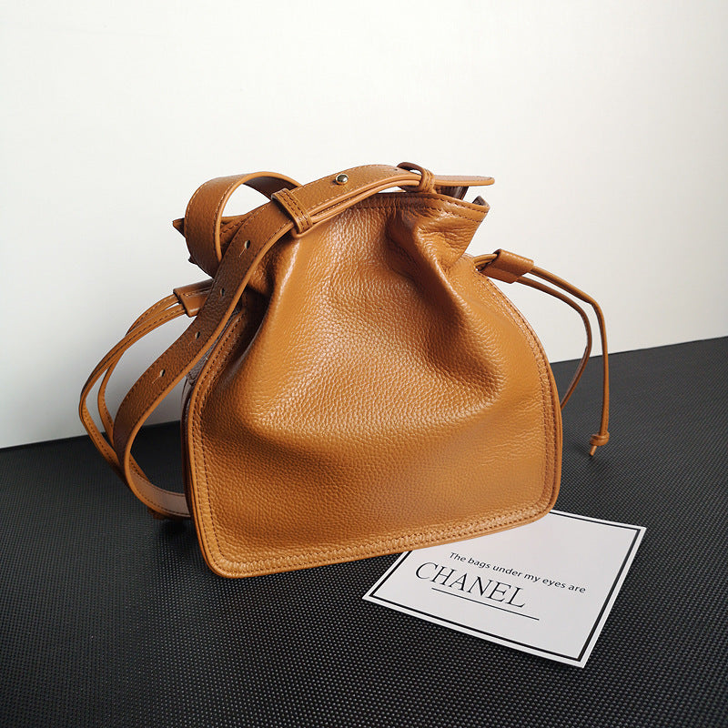 Brown leather handbag on a black surface with a Chanel card in the foreground