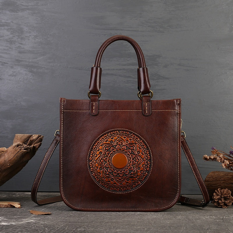 Brown leather handbag with decorative circular pattern on a gray background