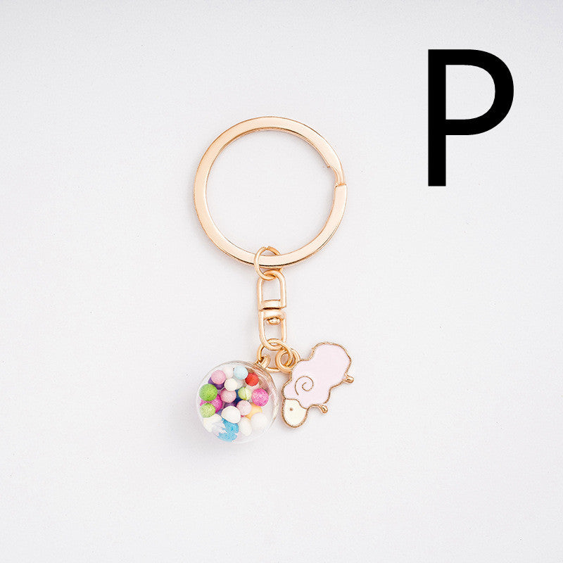Gold keychain with colorful charm and pink heart on a white background
