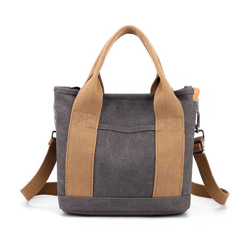 Gray tote bag with brown handles and strap on a white background