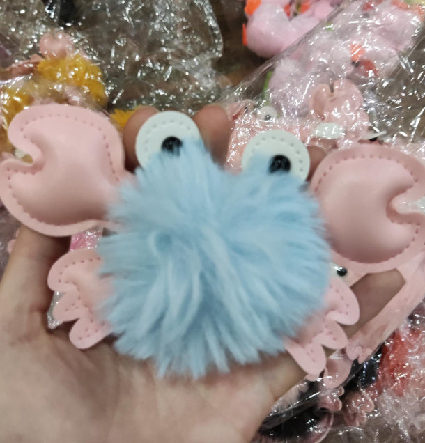 Heart-shaped blue plush toy held in a hand with pink heart-shaped