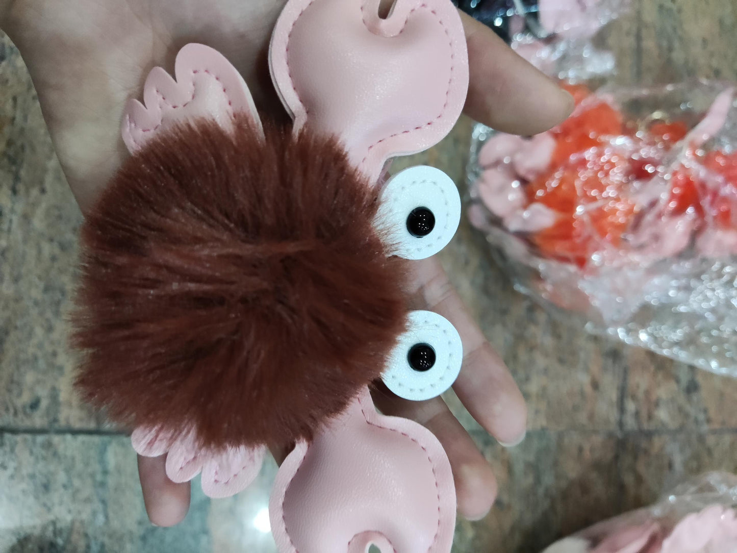 Hedgehog-shaped keychain with pink ears and brown body held