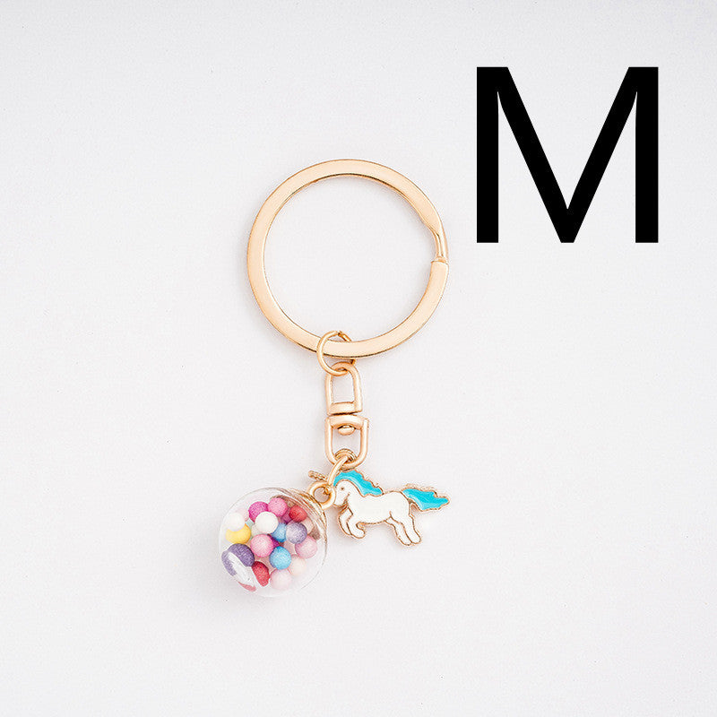 Keychain with a unicorn and candy jar charm on a light gray background