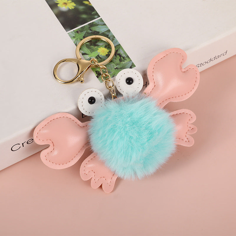 Keychain with pink heart-shaped wings and a turquoise pom-pom