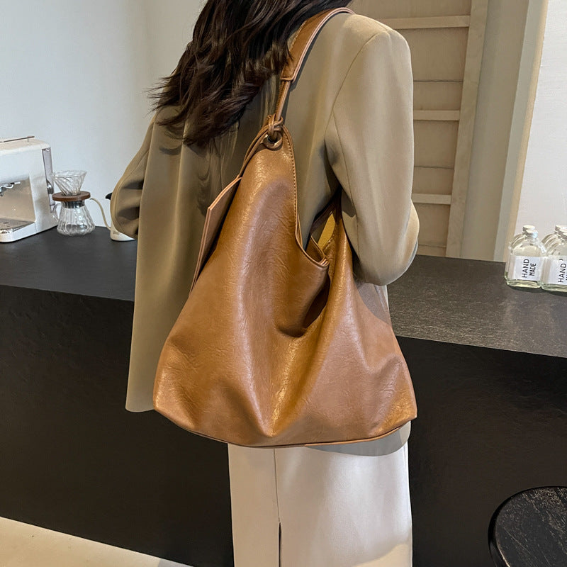 Person holding a brown leather handbag in an indoor setting