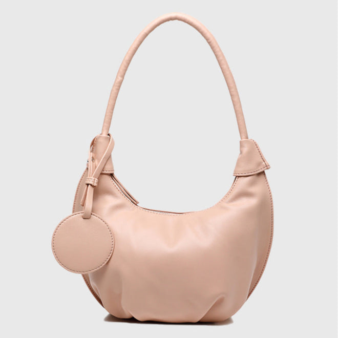 Pink handbag with a round tag on a light gray background