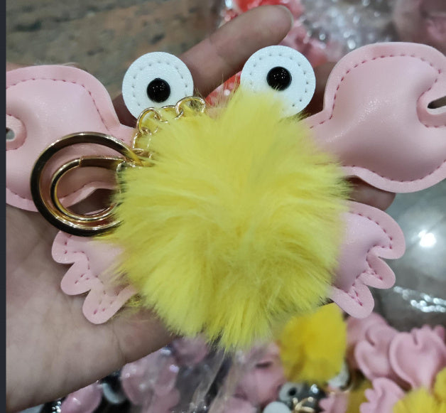 Pink keychain with yellow fuzzy ball and googly eyes