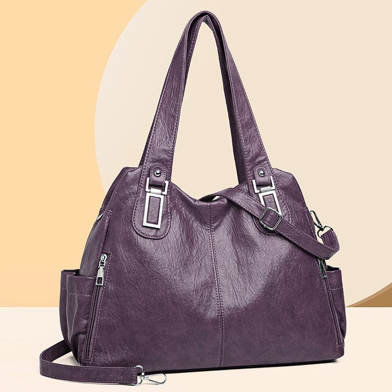 Purple handbag with multiple straps on a beige background