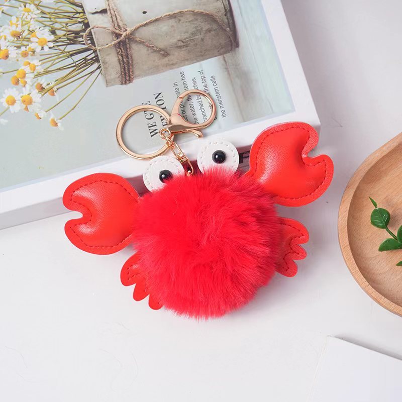 Red crab-shaped keychain with a fluffy pom-pom