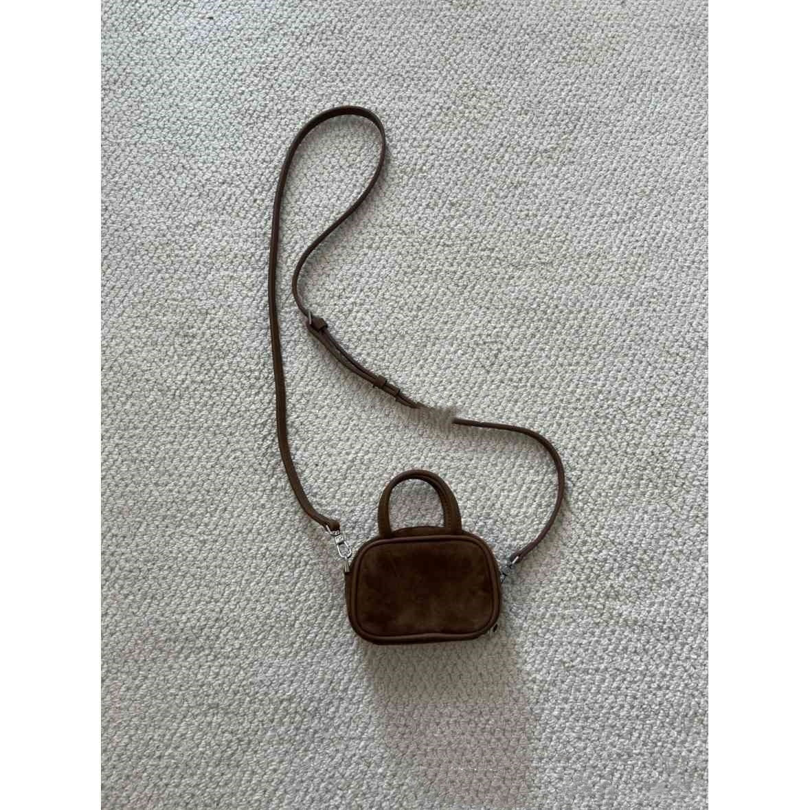 Small brown handbag with a strap on a textured gray background