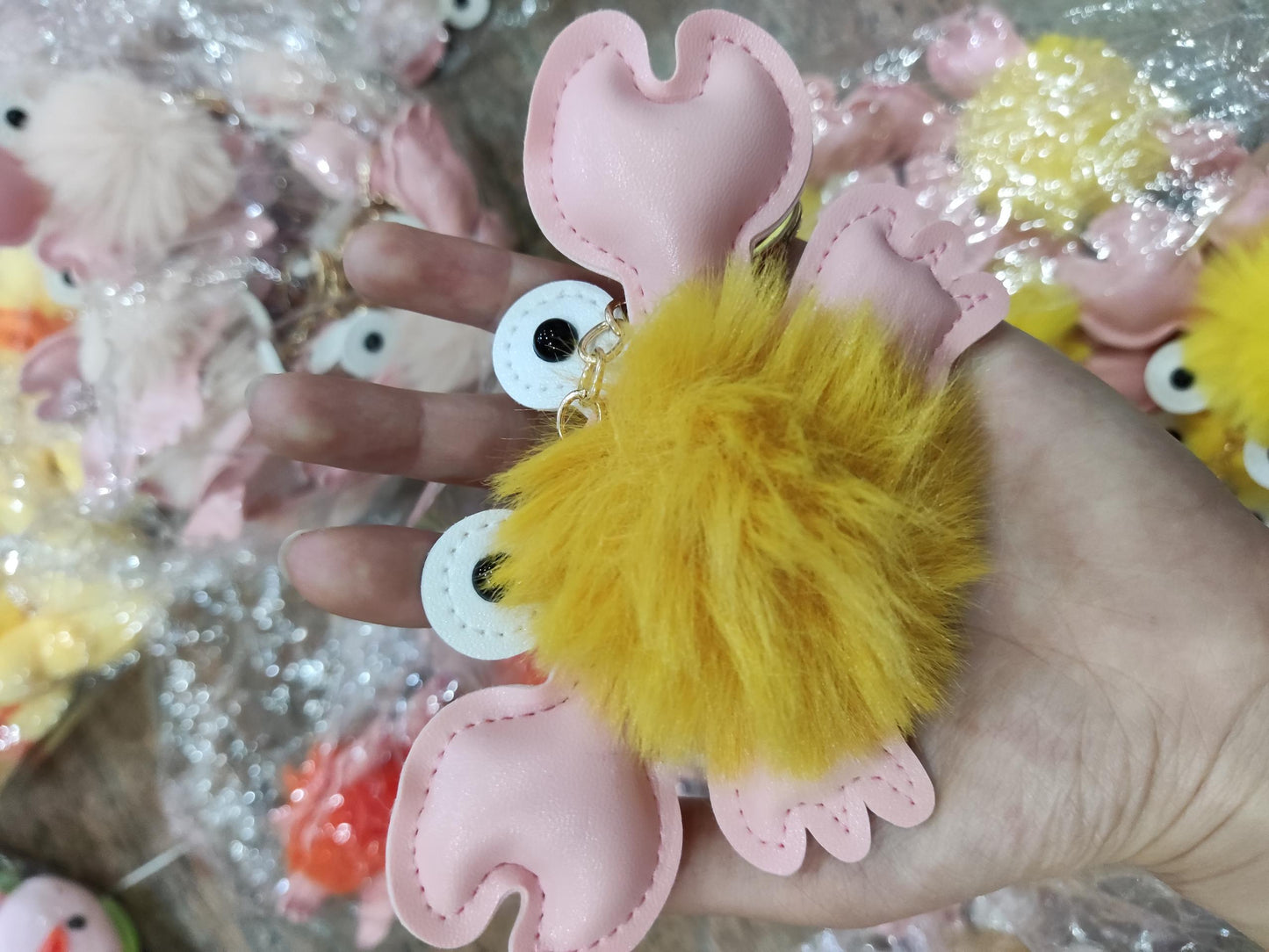 Yellow fluffy keychain held by a hand