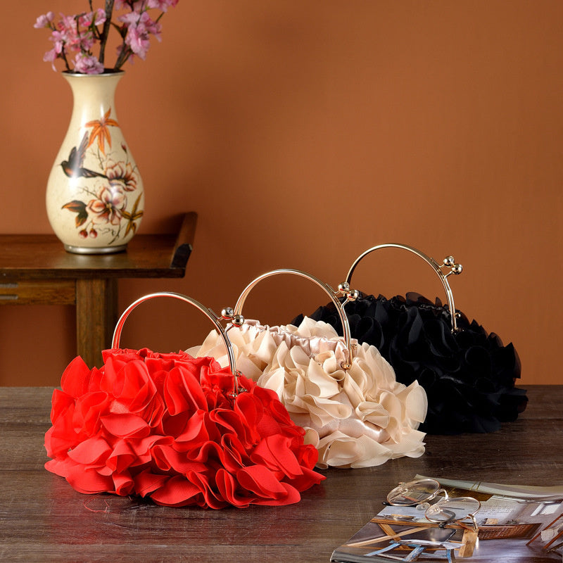 Three floral handbags in red, beige, and black on a wooden table with a vase in the background.