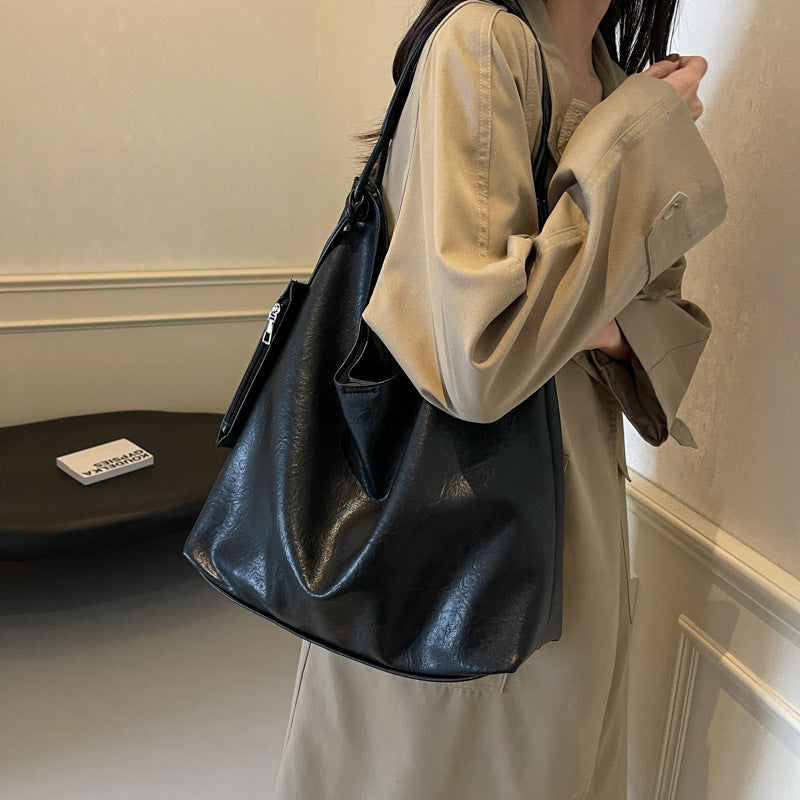 Person holding a black leather handbag indoors
