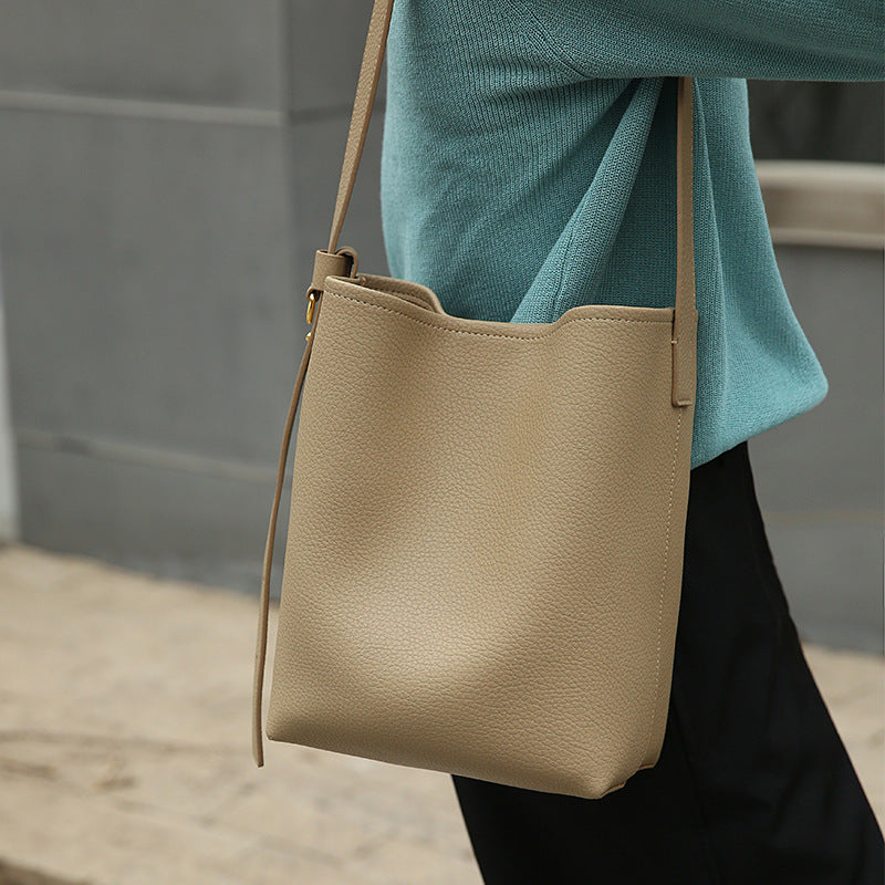 Close-up of cowhide leather texture and stitching on crossbody bucket bag