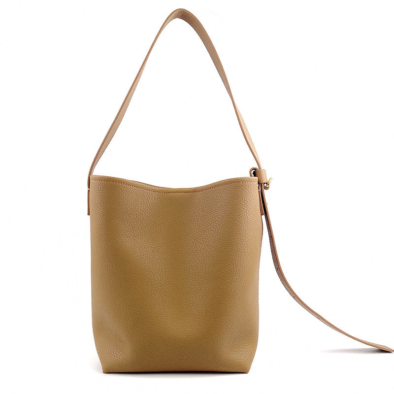 Woman styling black leather crossbody bucket bag with everyday outfit