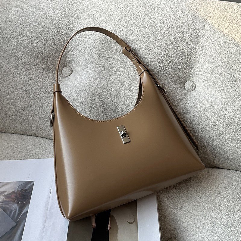 Woman carrying white leather crossbody bag with lock element