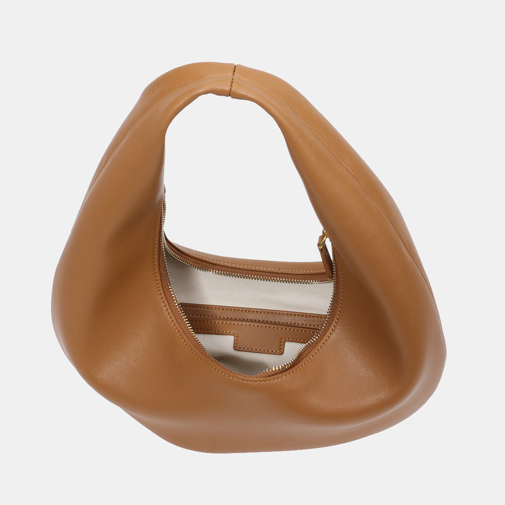 Model holding brown minimalist cowhide shoulder purse