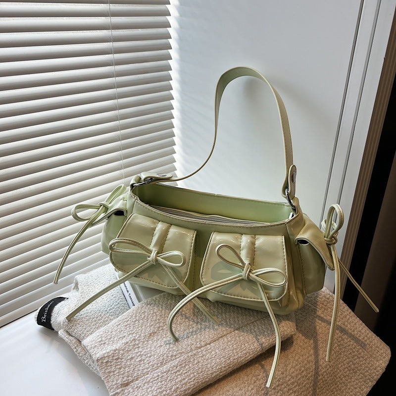 Side view of multi-pocket pleated shoulder bag with bow