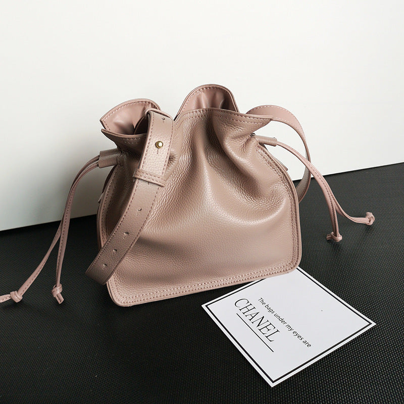 Flat lay of square vertical cowhide pull-belt bucket bag with props