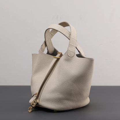 Beige handbag with gold accents on a gray surface and light gray background