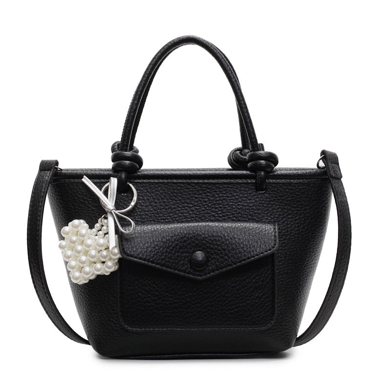 Black handbag with a pearl charm on a white background