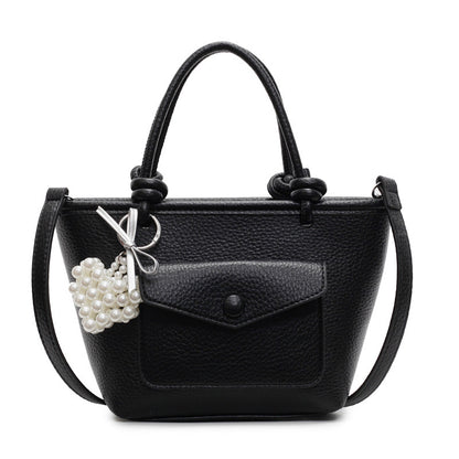 Black handbag with a pearl charm on a white background