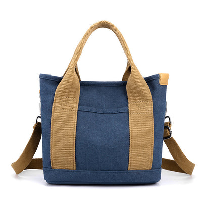 Blue tote bag with brown handles and strap on a white background