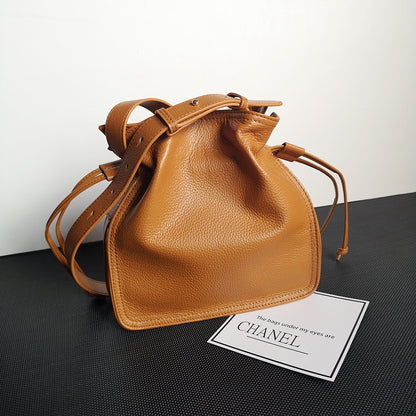 Brown leather handbag on a black surface with a Chanel card in the foreground