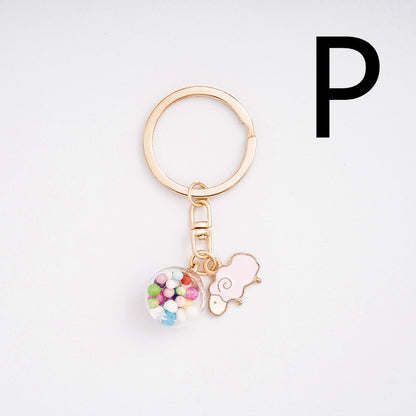 Gold keychain with colorful charm and pink heart on a white background