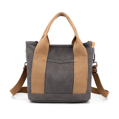 Gray tote bag with brown handles and strap on a white background