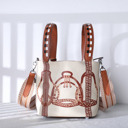 Handbag with brown leather straps and intricate design on a light background