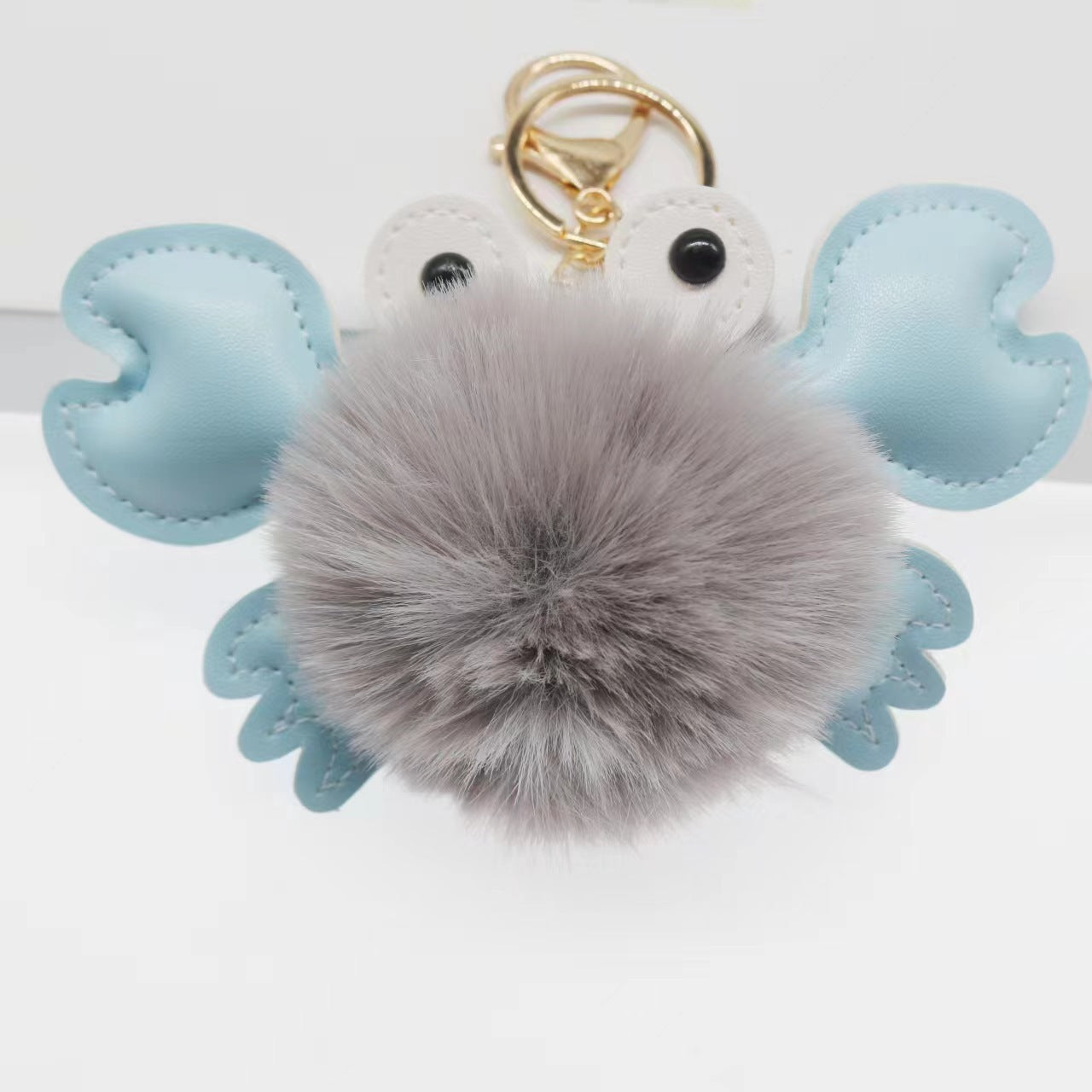 Keychain with a gray fluffy ball and blue heart-shaped wings
