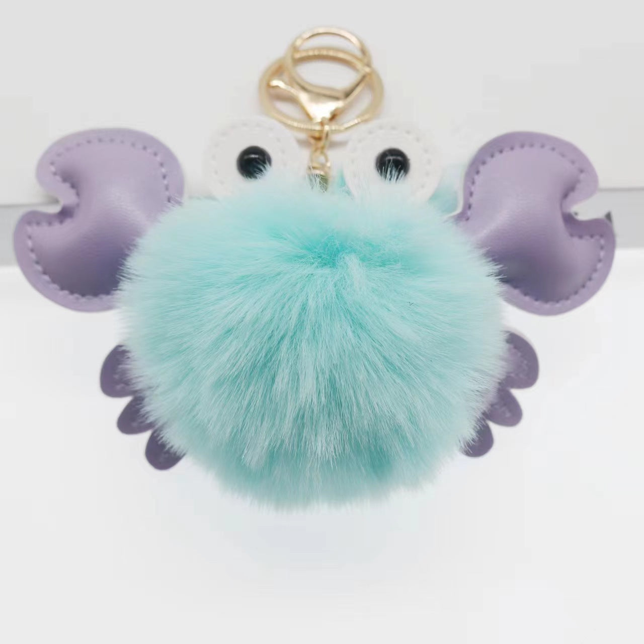 Keychain with a teal pom-pom and purple butterfly wings 