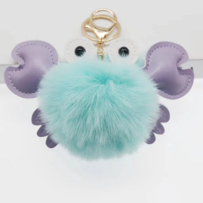 Keychain with a teal pom-pom and purple butterfly wings 