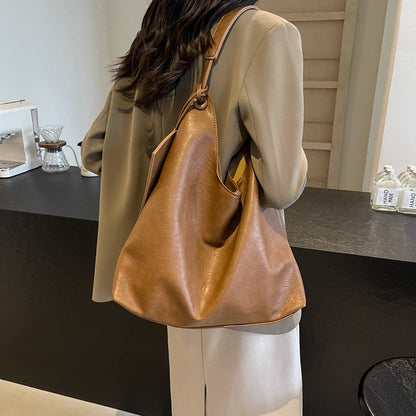 Person holding a brown leather handbag in an indoor setting
