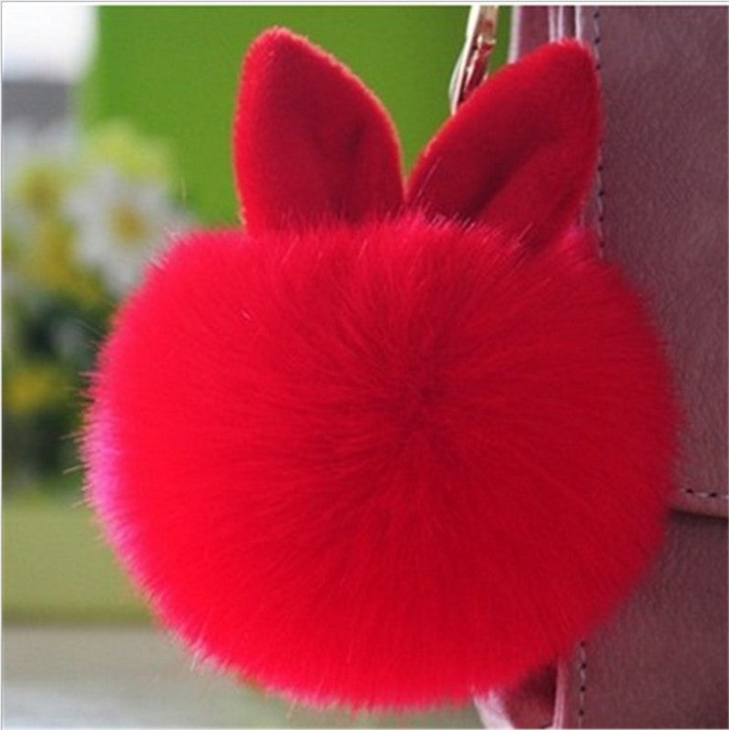 Red fluffy keychain with bunny ears on a blurred background