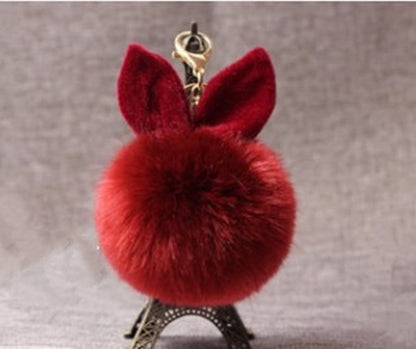 Red fluffy keychain with gold accents on a gray background