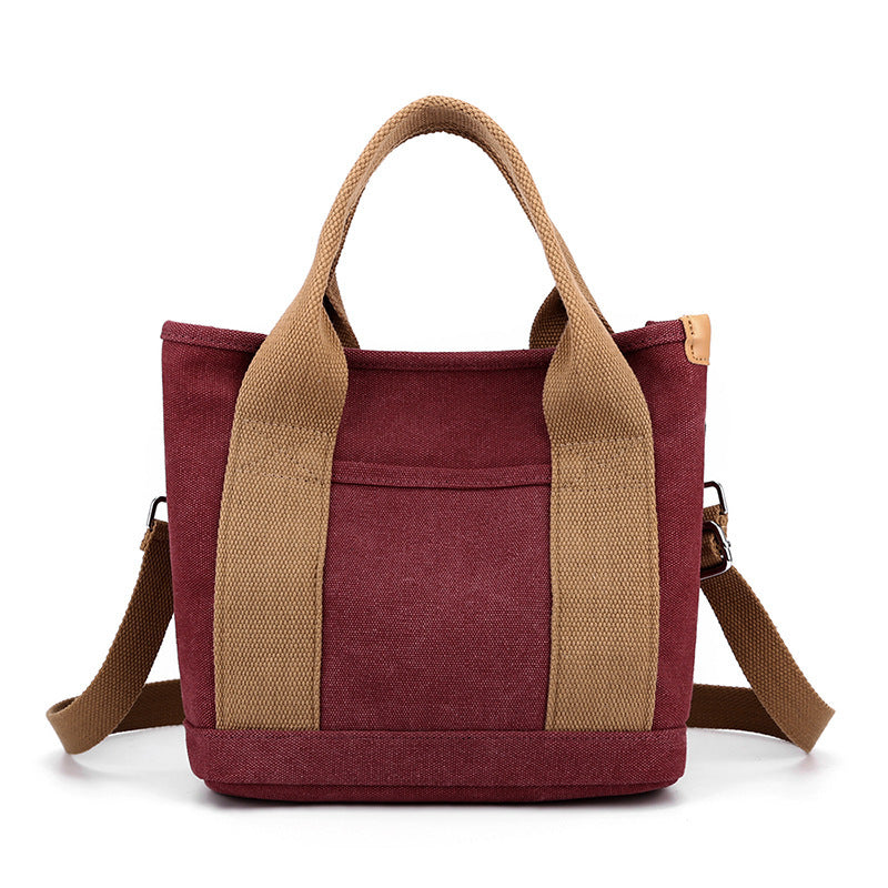 Red tote bag with brown handles and strap on a white background