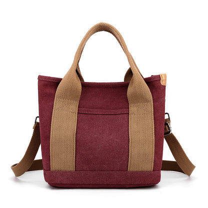 Red tote bag with brown handles and strap on a white background