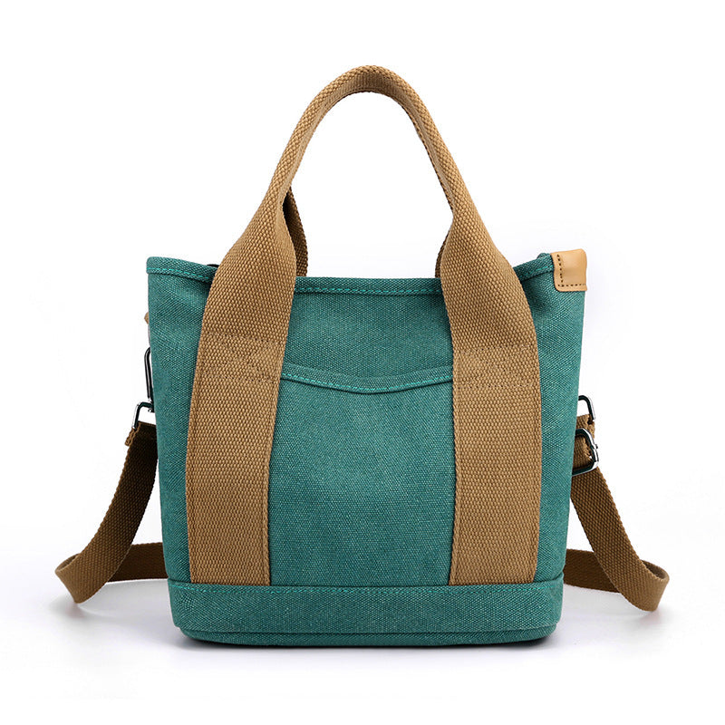 Teal tote bag with brown handles and strap on a white background