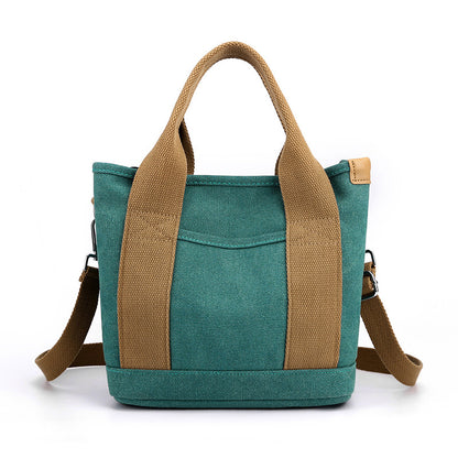 Teal tote bag with brown handles and strap on a white background