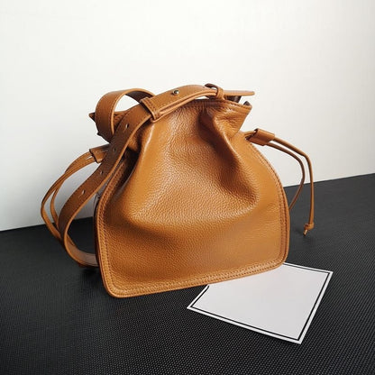 Close-up of brown cowhide pull-belt bag strap and stitching details