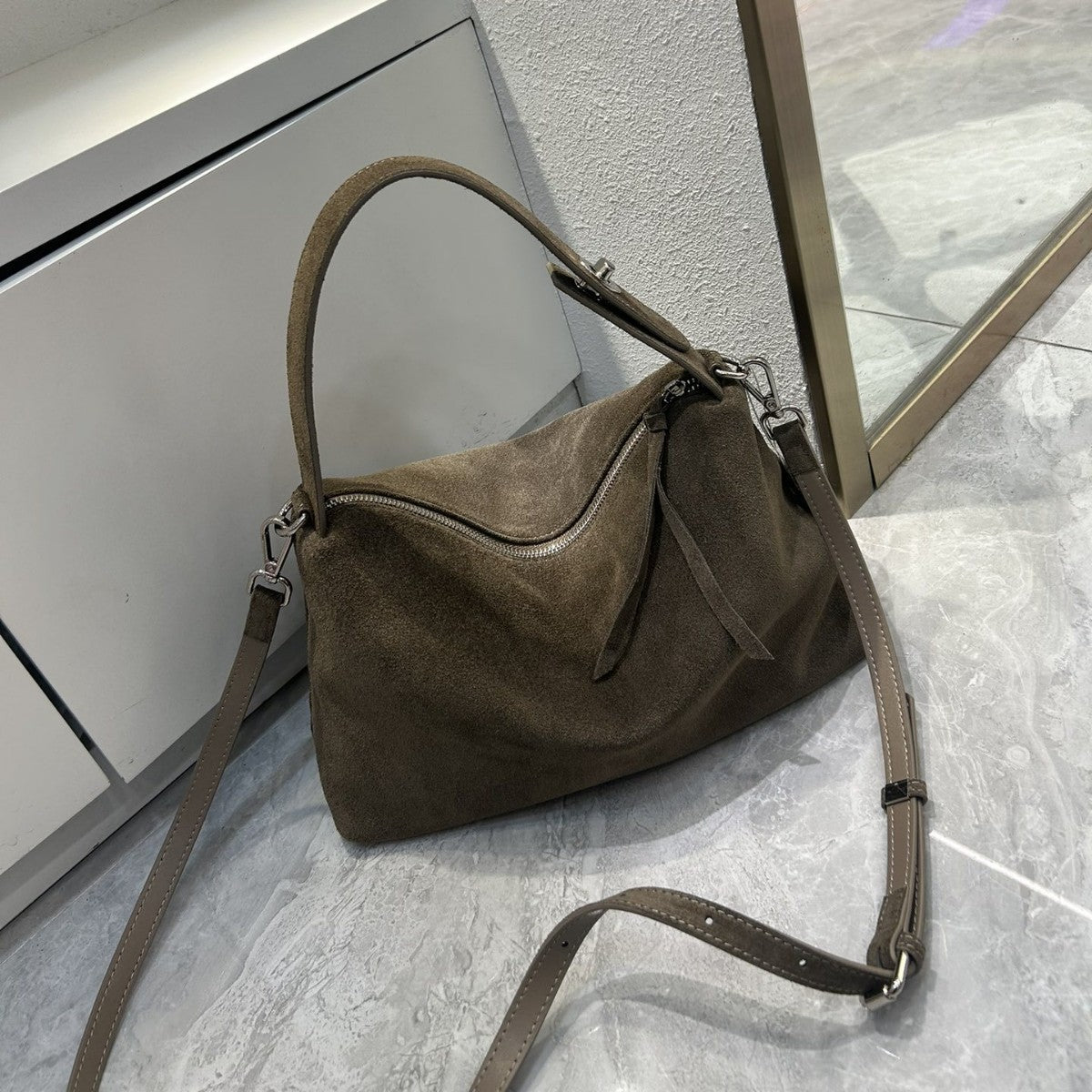 Brown suede handbag on a gray tiled floor