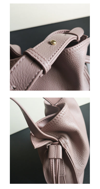 Side angled view of burgundy cowhide pull-belt crossbody bucket bag