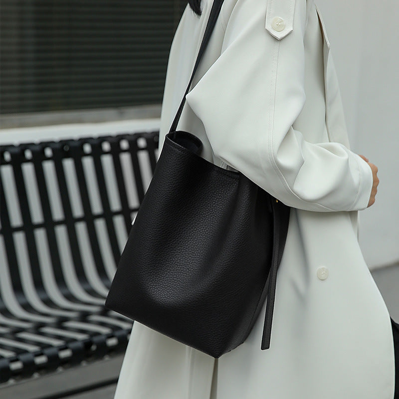 Flat lay of cowhide bucket crossbody bag with daily items