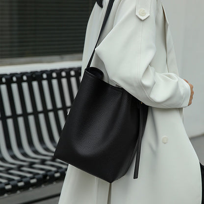 Flat lay of cowhide bucket crossbody bag with daily items