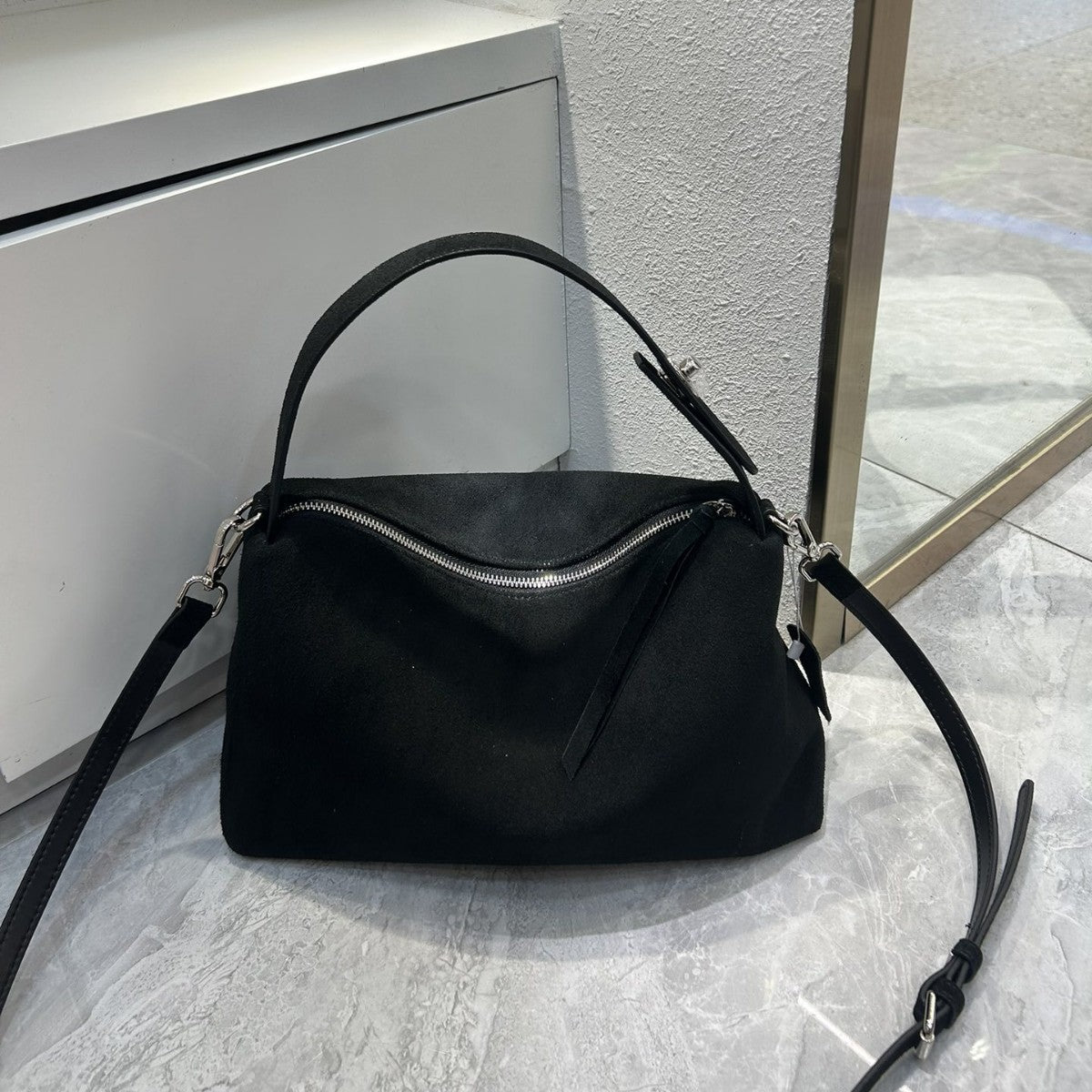 Black handbag on a light gray surface with a neutral background