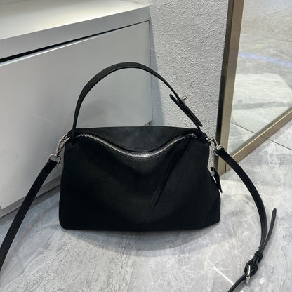 Black handbag on a light gray surface with a neutral background