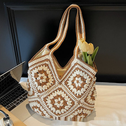 Crocheted bag with floral pattern on a desk next to a laptop
